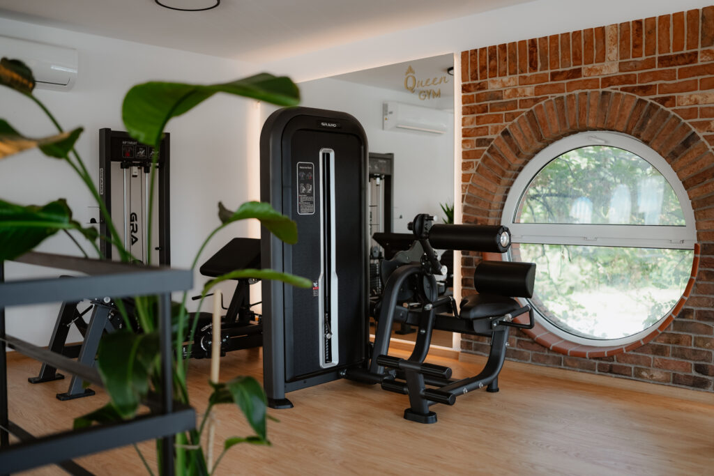 Posilňovací stroj pri okrúhlom okne v Queen Gym Trnava